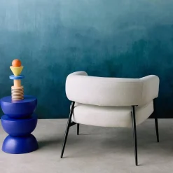 Sillón de tela con respaldo curvo y patas de metal
