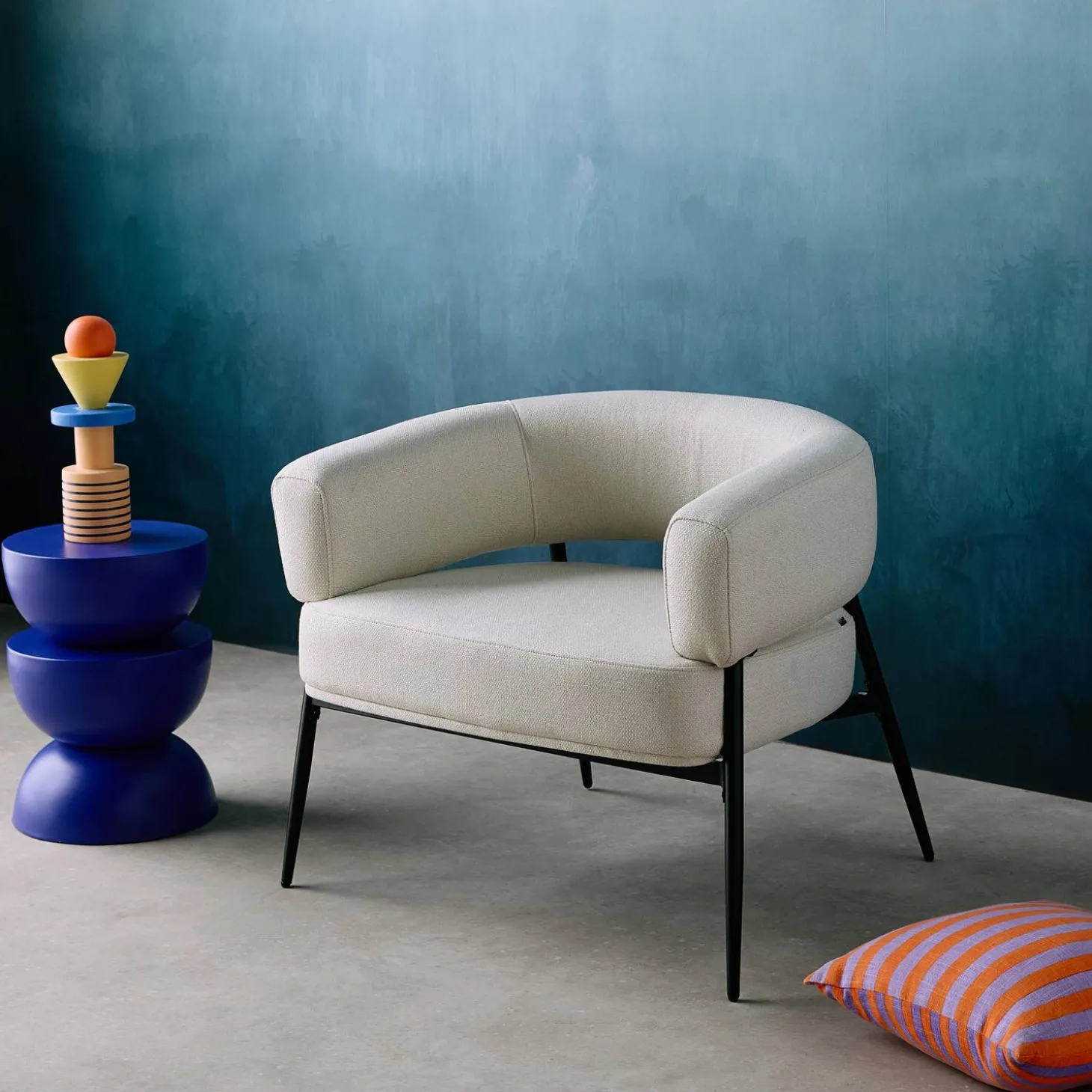 Sillón de tela con respaldo curvo y patas de metal