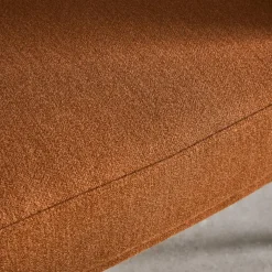 Sillón de tela con respaldo curvo y patas de metal
