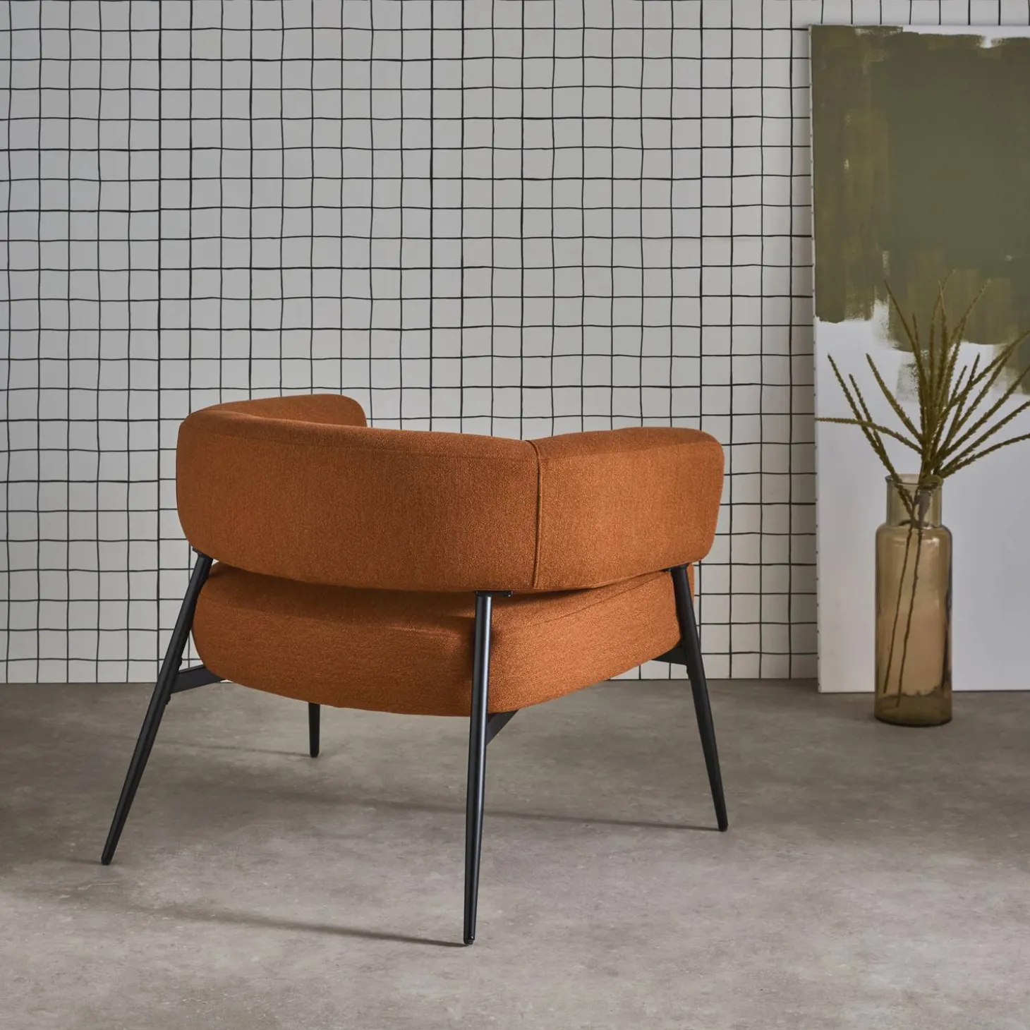 Sillón de tela con respaldo curvo y patas de metal