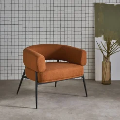 Sillón de tela con respaldo curvo y patas de metal