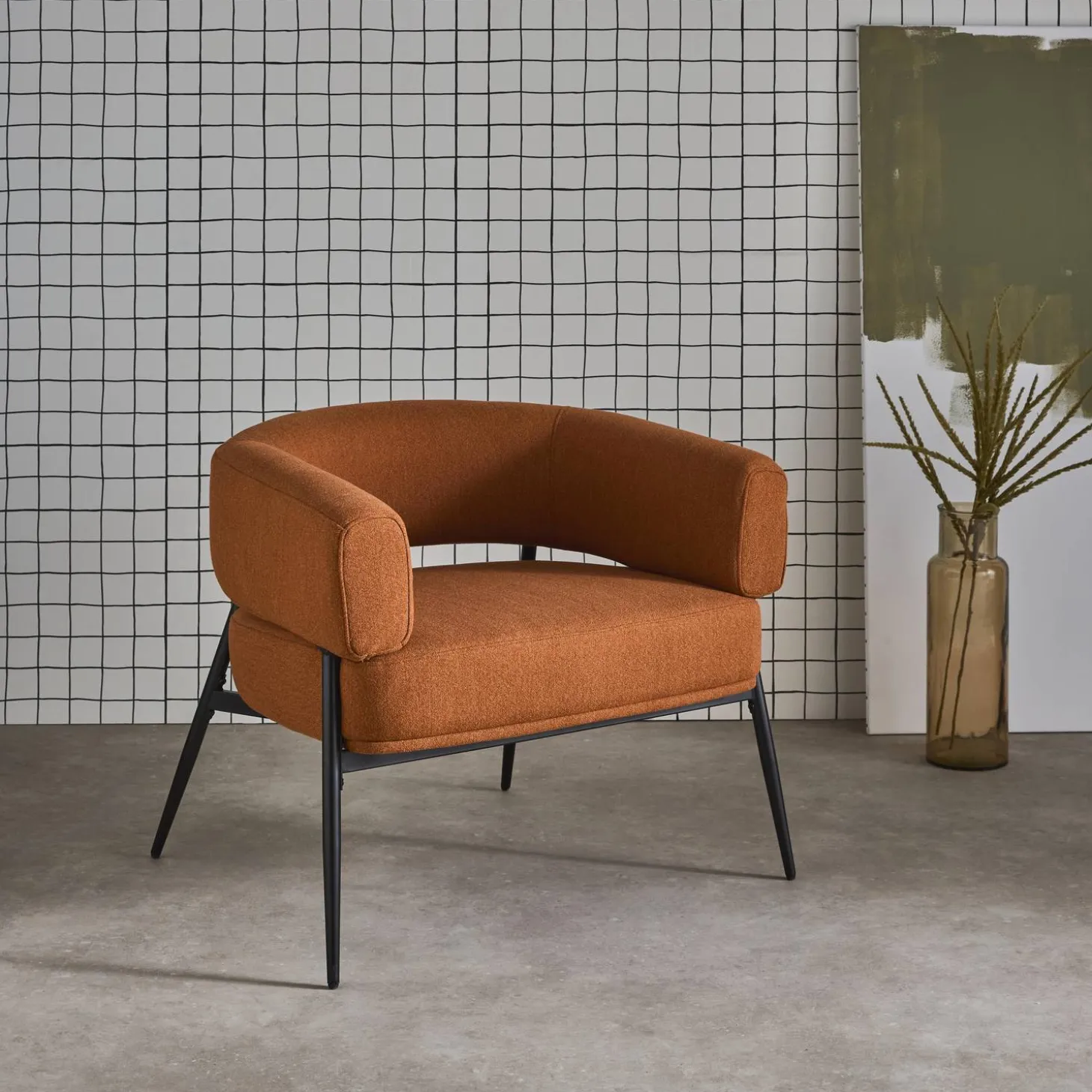 Sillón de tela con respaldo curvo y patas de metal