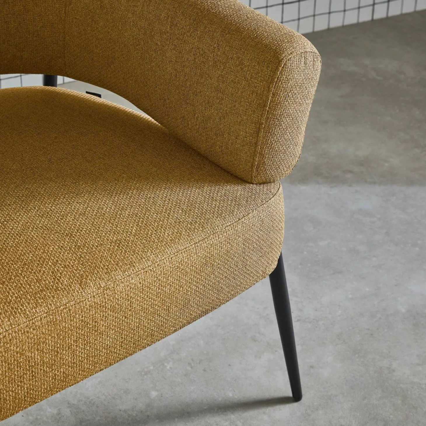 Sillón de tela con respaldo curvo y patas de metal