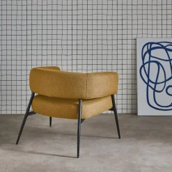 Sillón de tela con respaldo curvo y patas de metal