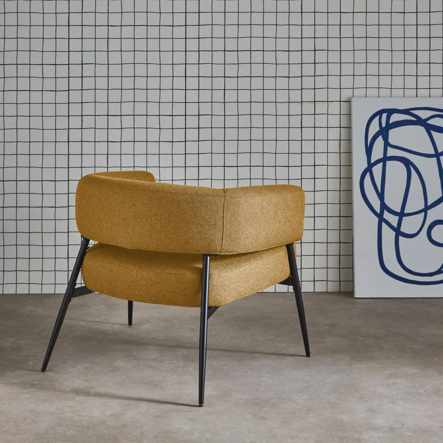 Sillón de tela con respaldo curvo y patas de metal