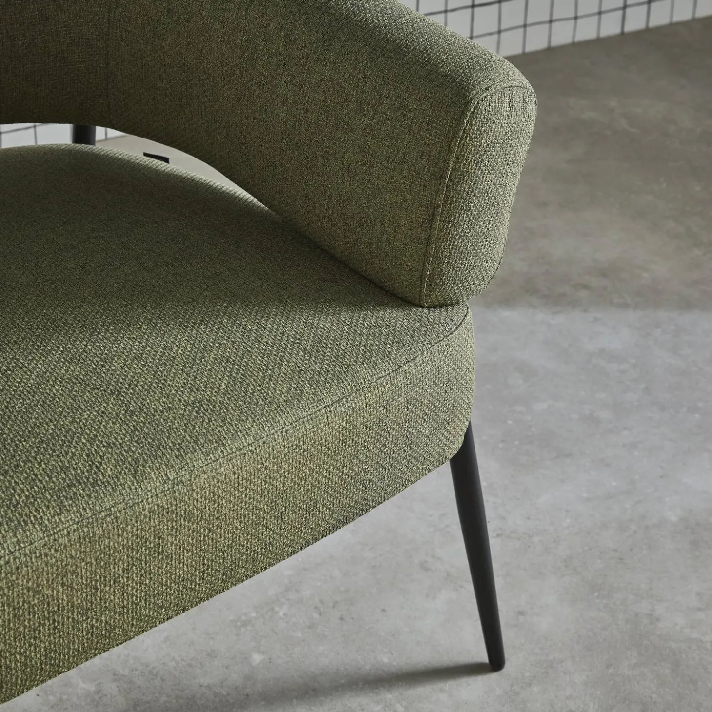 Sillón de tela con respaldo curvo y patas de metal