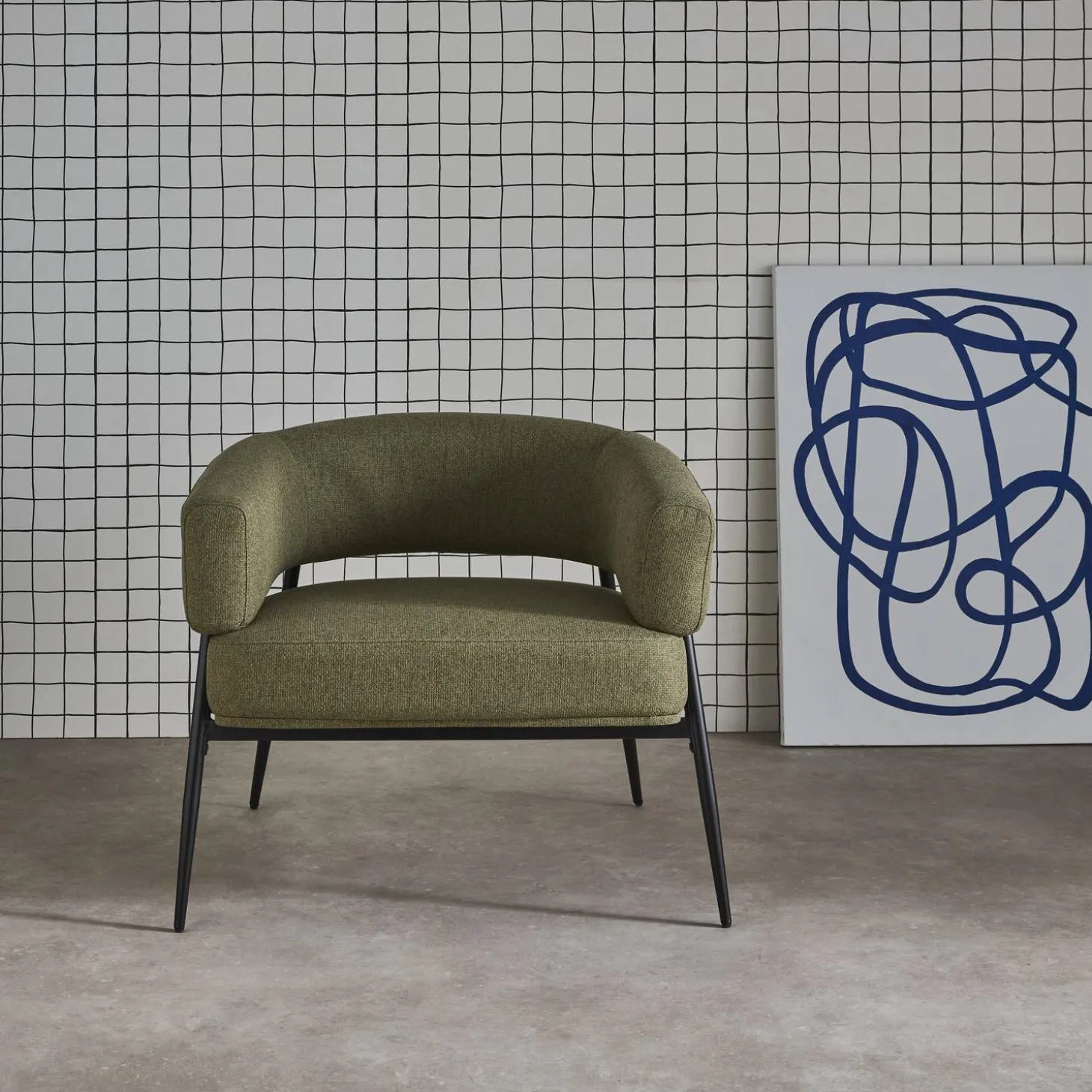 Sillón de tela con respaldo curvo y patas de metal