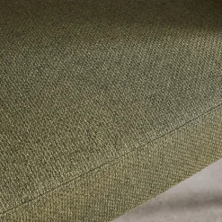 Sillón de tela con respaldo curvo y patas de metal