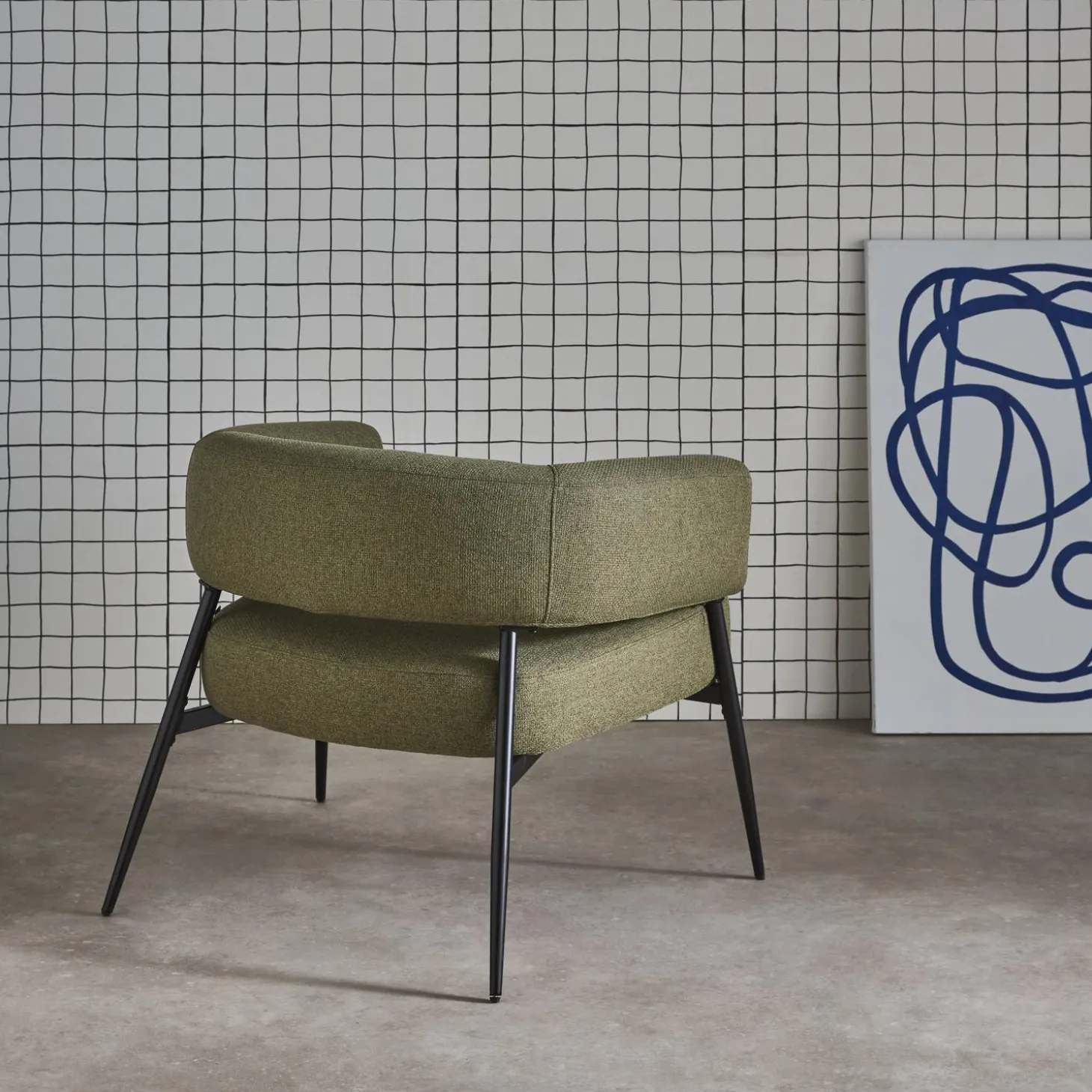 Sillón de tela con respaldo curvo y patas de metal